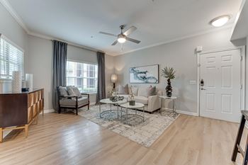 A living room with a white couch, a wooden table, and a ceiling fan at Limestone Ranch Apartments, Lewisville, TX